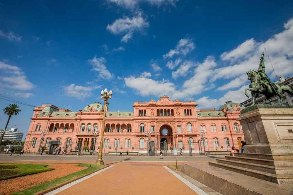 Casa Rosada, et stort rosa administrativt bygg med rytterstatue foran under blå himmel.